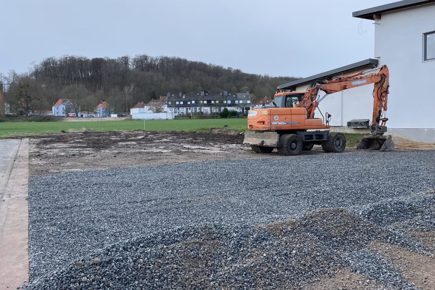 Lagerfläche vor den Arbeiten: Eingebaute Schottertragschicht, Bagger auf der Fläche
